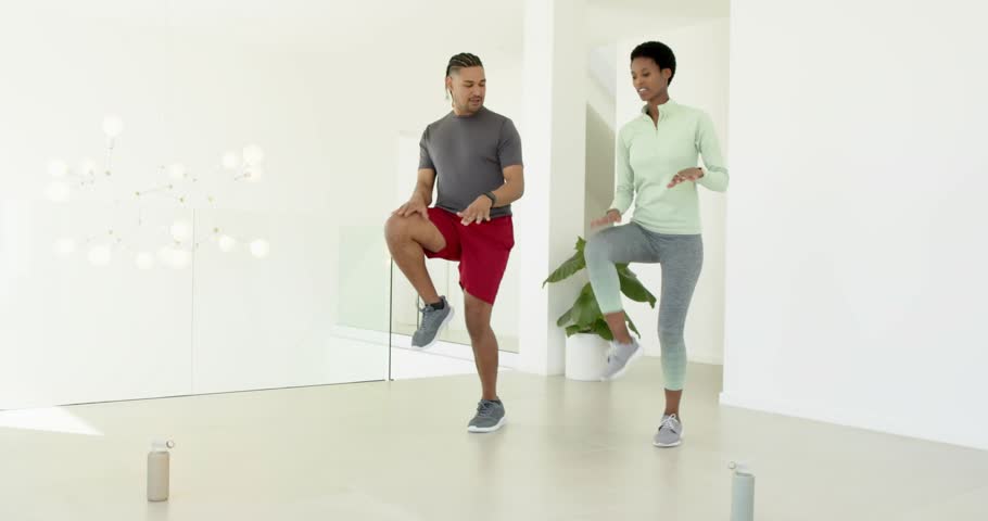 Man tapping knee on speaker, syncing fitness steps, woman mirroring as UI icons floating. Fitness, choreography, digital interface, smart technology, home workout, modern lifestyle, rhythmic movement