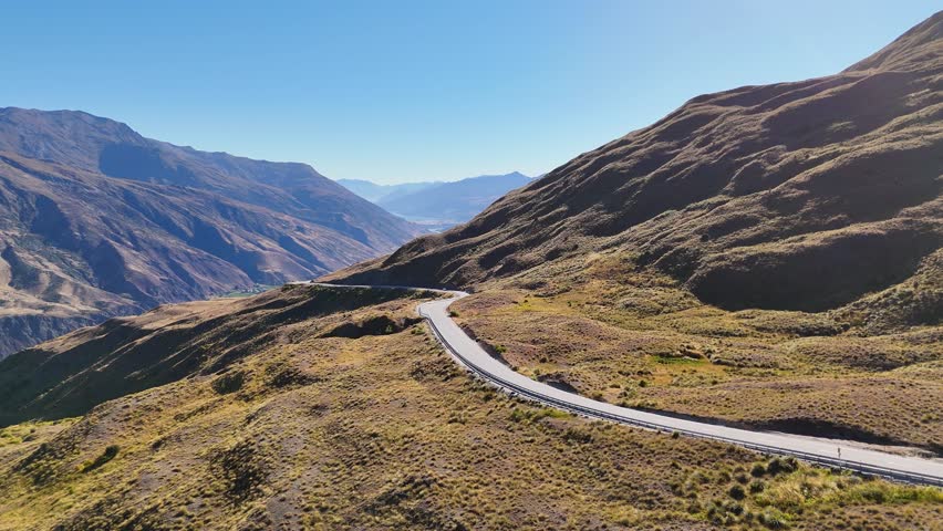 4K drone captures the Crown Range Road, the highest road in New Zealand. Winding alpine roads, mountains, and valleys create a stunning aerial view of the South Island landscape.