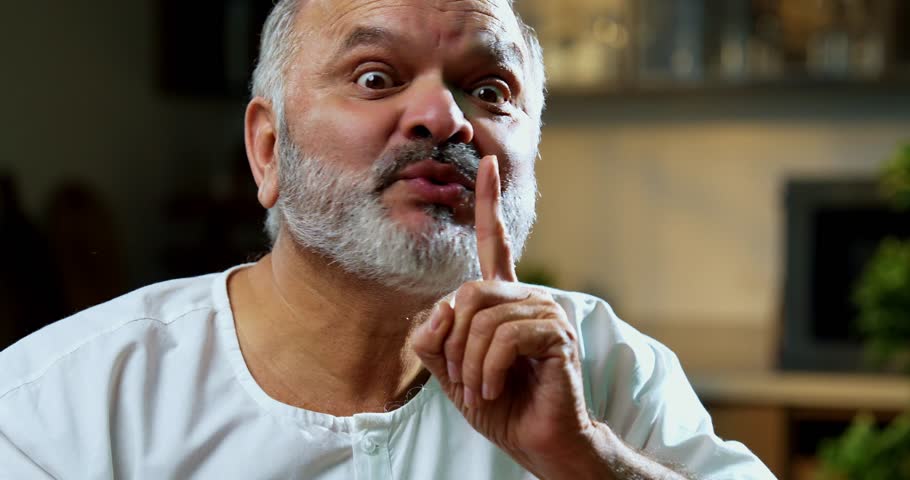 Senior Indian man eating sweet gulab jamun secretly at home, Asian foodie old man expressing immense joy, delight while enjoying delicious Indian dessert at table in bright modern kitchen interior