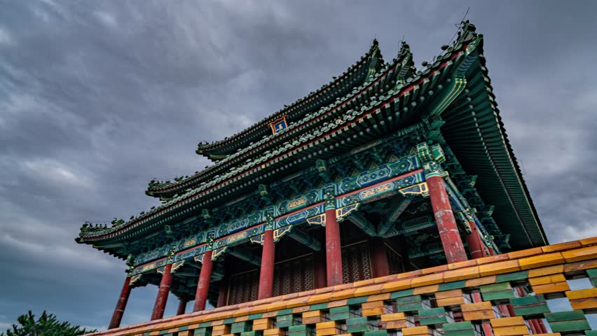 Traditional Chinese Wanchun Pavilion at Jingshan Park in Beijing showcasing ancient imperial architecture with ornate colorful details against dramatic cloudy sky in 10K timelapse quality.