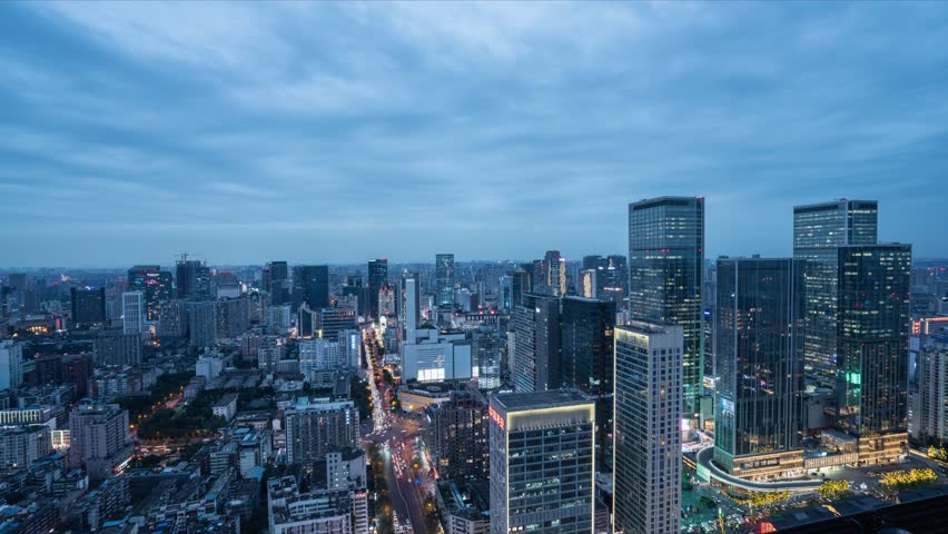 Aerial view of Chengdu city skyline at dusk with illuminated skyscrapers, busy streets, and urban traffic in Jinjiang district, perfect for timelapse video production.