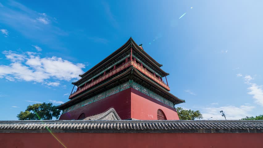Timelapse view of historic Beijing Drum Tower with traditional Chinese architecture against blue sky with white clouds in China