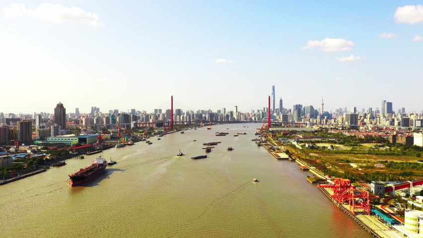 Aerial view of Shanghai cityscape with Huangpu River, cargo ships, port cranes, and modern skyline showcasing China