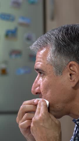 A 55-year-old, Gray-haired Man Eating Grilled Chicken, Grilled Zucchini, and Tomato Salad. Middle-aged Man in a Plaid Shirt is Sitting at a Dining Table, Enjoying Lunch in the Peace of his Apartment.