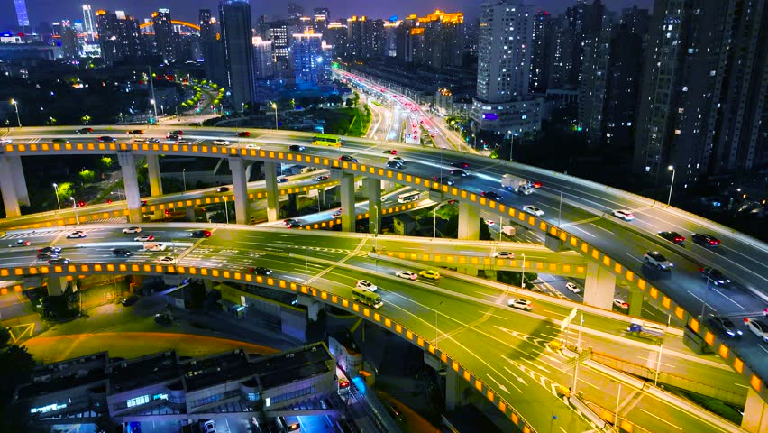 An aerial view of a busy illuminated multi-level highway interchange with moving car traffic at night, Shanghai, China.