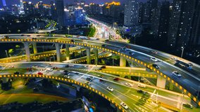 Aerial view of a complex highway interchange with illuminated traffic flowing through multiple road layers, surrounded by urban skyscrapers at night in Shanghai, China. - Powered by Shutterstock - Get 15% off with code: PIKWIZARD15