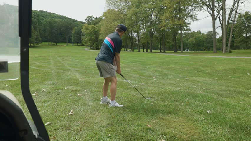Golfer takes a clean shot from the fairway on a scenic, green golf course.