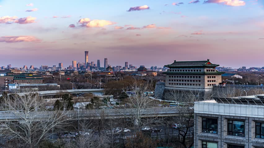Beijing cityscape at sunset showing Deshengmen Bell Tower and modern skyscrapers, blending ancient Chinese architecture with contemporary urban development.