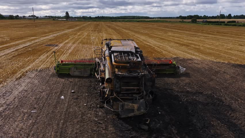 Burned harvester in field reflects war destruction and strength to rebuild again