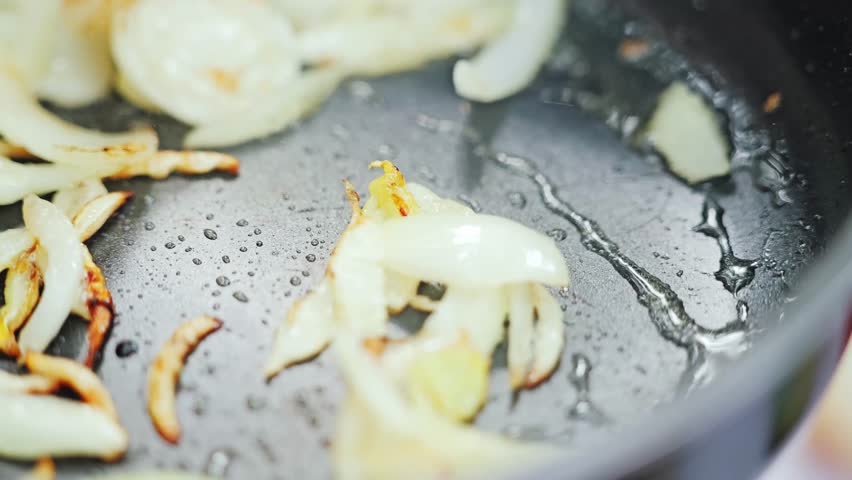 Golden onions cooking in camping stove pan with rustic atmosphere slow motion