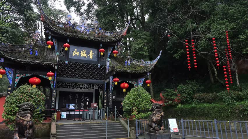 Traditional Chinese temple entrance with red lanterns and ornate architecture at Qingcheng Mountain scenic spot near Chengdu, China surrounded by lush green forest.