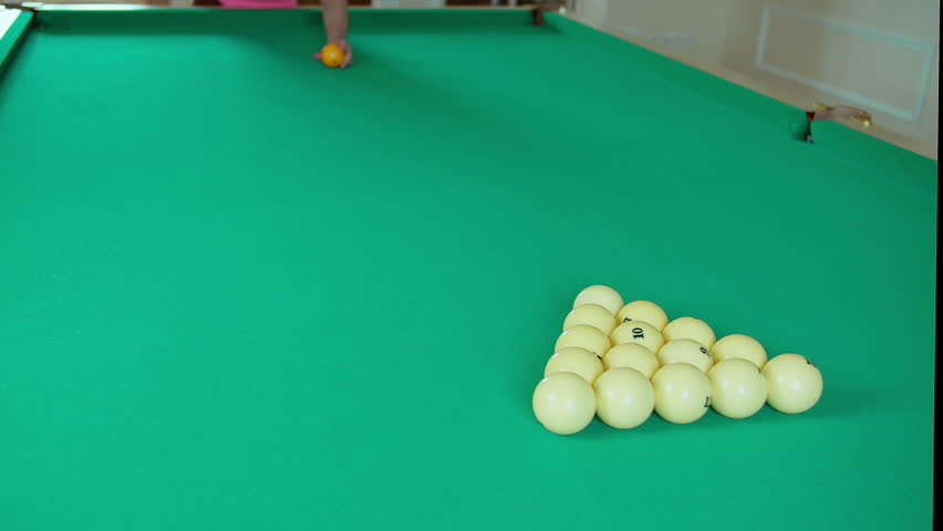 Player in billiards, cue breaks the pyramid of billiard balls, the game of Russian billiards
