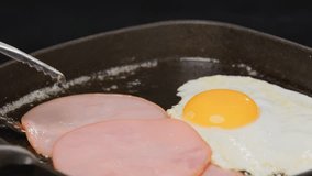 Fresh ham and fried egg cooking in cast iron skillet, perfect sunny side up breakfast with golden yolk and crispy edges in traditional frying pan. - Powered by Shutterstock - Get 15% off with code: PIKWIZARD15
