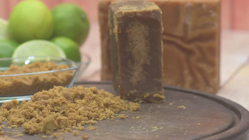 Static insert shot detailing the preparation of sugarcane limeade, showing a knife and spoon covered with granular raw sugar (panela) next to the essential lime ingredients.