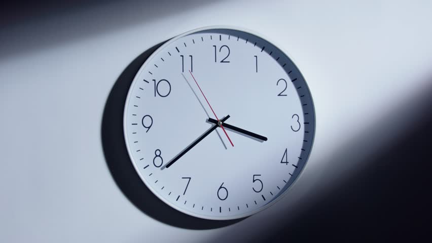 White wall clock with black hands and red second hand showing time, representing fast-paced time management and urgency in business and daily life.