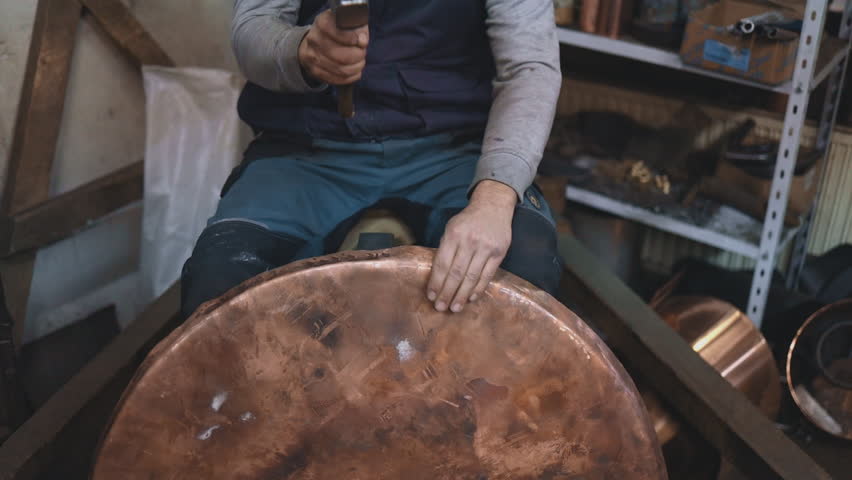 Traditional coppersmith workshop for copper brewing pots manufacturing. This handmade brewery kettles will be used for making traditional alcohol brandy drinks. Small traditional business concept.