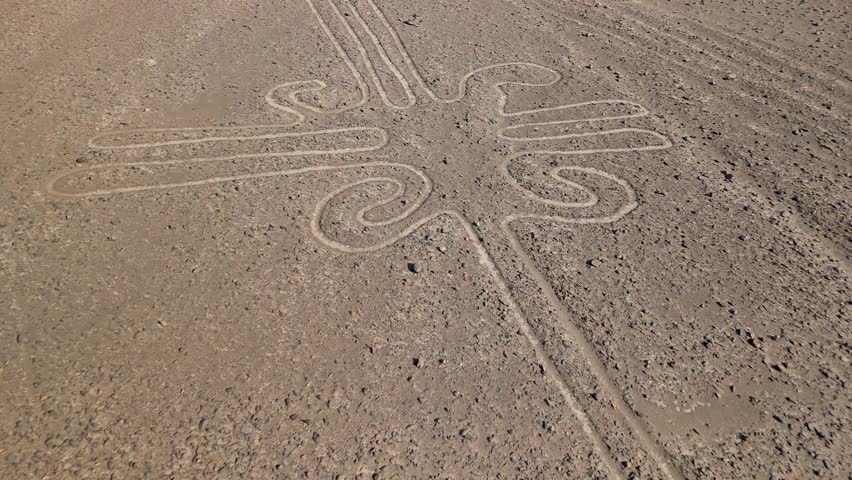 Descending aerial flight over the mysterious and ancient Nazca Lines geoglyphs with a slow tilt up revealing the vast desert landscape of Peru