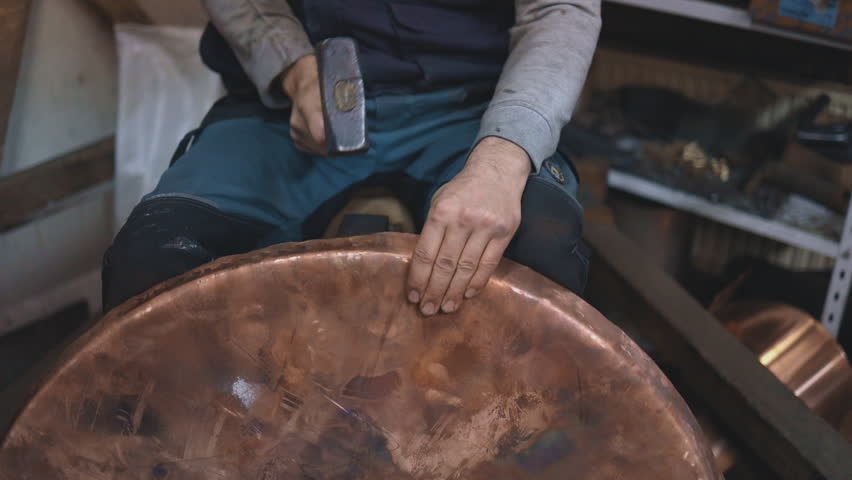 Traditional coppersmith workshop for copper brewing pots manufacturing. This handmade brewery kettles will be used for making traditional alcohol brandy drinks. Small traditional business concept.