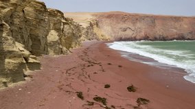 Low aerial tracking shot flying along the unique red sand beach of Playa Roja as waves wash ashore next to desert cliffs in Paracas Reserve - Powered by Shutterstock - Get 15% off with code: PIKWIZARD15