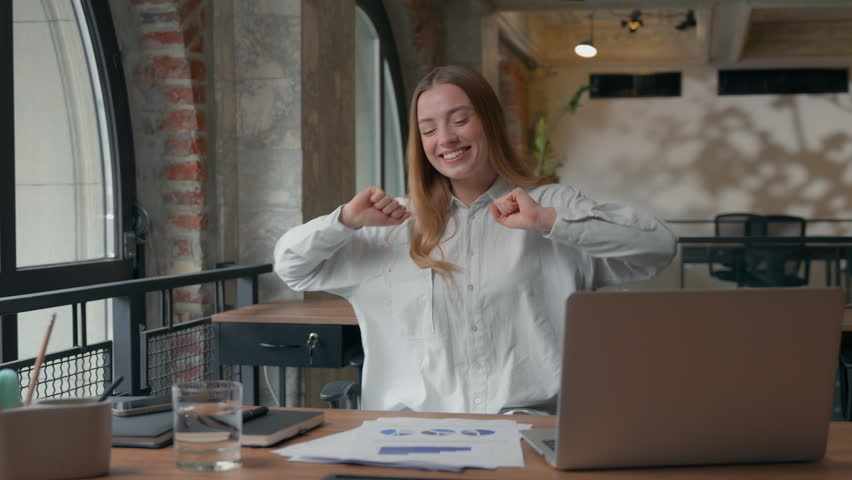 Joyful smiling Caucasian business woman female entrepreneur girl businesswoman having fun joy spinning rotate on office chair dancing showing thumbs up happy with corporate success documenting results