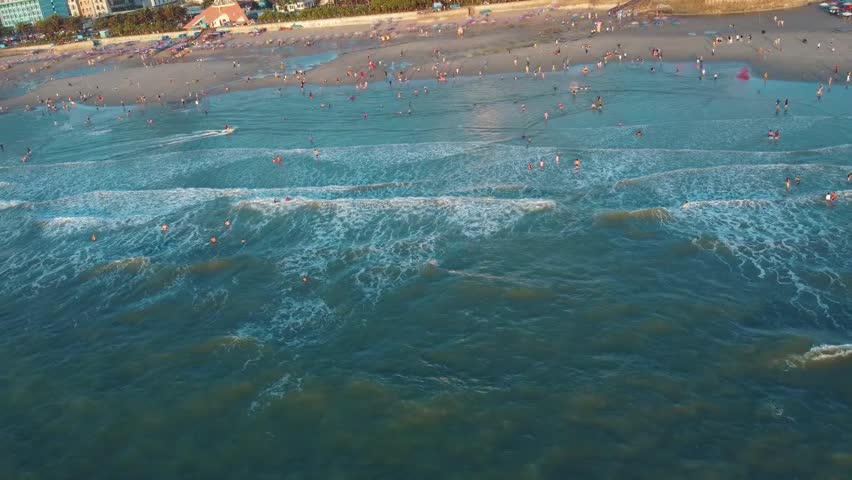 Drone video capturing My Khe Beach, Da Nang, Vietnam during peak hours. Aerial footage showcasing bustling roads, ocean views, vibrant cityscape with serene coastal waters.