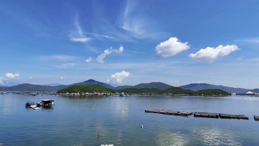 Scenic aerial footage of Cam Ranh Bay, Vietnam, showcasing serene waters, lush islands, and vibrant skies. Captures tranquil beauty with floating structures under bright, crisp daylight.