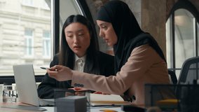 Two busy females multiracial business team women cooperation with online internet laptop work and documents diversity businesswomen girls talking managing papers Asian woman Muslim girl in office - Powered by Shutterstock - Get 15% off with code: PIKWIZARD15