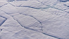 Aerial view showing fractured sea ice shifting from subtle surface cracks to open leads and drifting floes, revealing thaw patterns and water channels across a frozen seascape. - Powered by Shutterstock - Get 15% off with code: PIKWIZARD15
