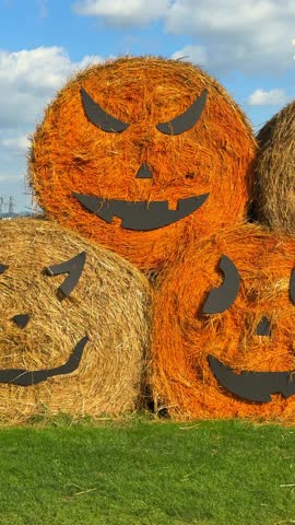 Cinematic view of dry hay bales decorated with spooky faces for Halloween at fair. Autumn festival decor, rustic seasonal display, playful and festive atmosphere, cinematic autumn scene