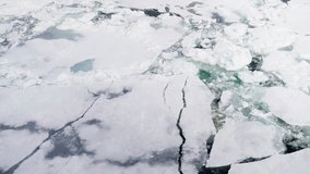Expansive aerial view of fractured sea ice, marked by long dark leads, fissures, and turquoise meltwater pools, exposing a fragile frozen ocean surface and seasonal breakup. - Powered by Shutterstock - Get 15% off with code: PIKWIZARD15