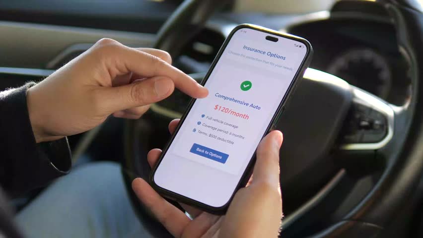 A man's hands hold a smartphone in a parked car, the screen displaying detailed terms and a price quote for auto insurance. His finger scrolls through the conditions, carefully reading and analyzing