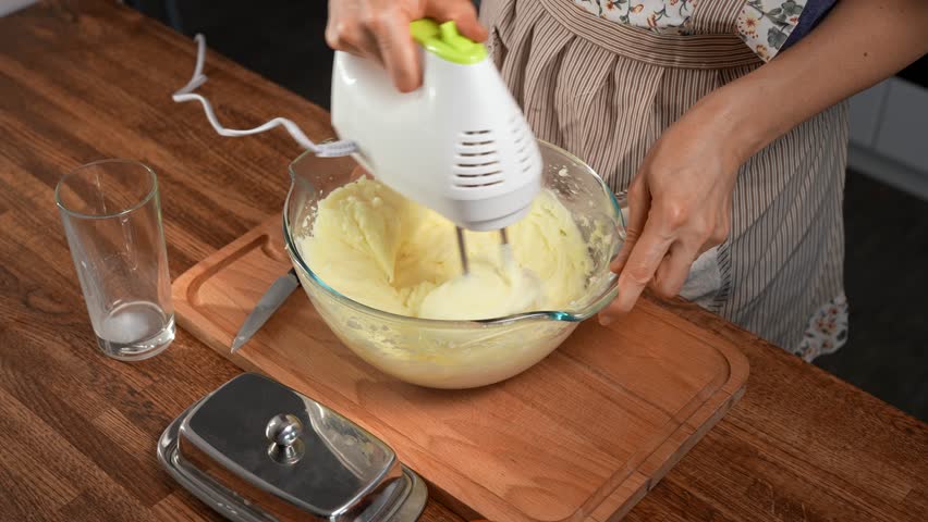 Woman using mixer to whip potatoes for mashed potatoes. Close-up, creamy.