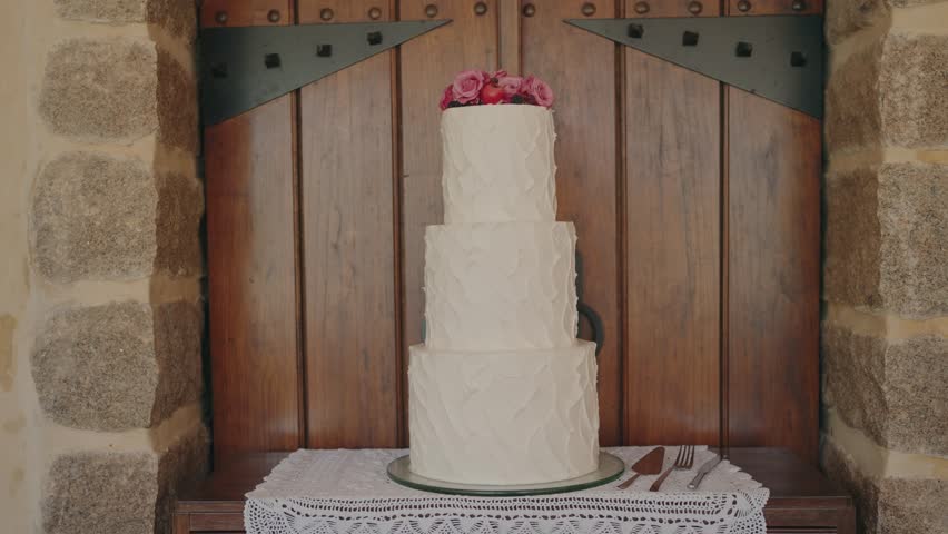 Elegant three tier white wedding cake decorated with pink roses