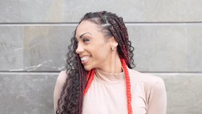 A fashionable woman adorned with stylish braided hair and eyecatching vibrant red accents beams with joy and happiness, set against a sleek and modern urban backdrop that enhances her beauty - Powered by Shutterstock - Get 15% off with code: PIKWIZARD15