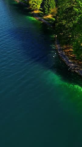 Aerial shot of Latvia lakeshore with green trees vibrant water and stone walkway highlighting the country