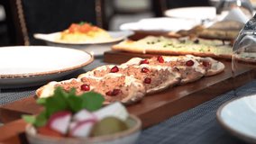 A beautifully arranged platter of Middle Eastern flatbreads garnished with pomegranate seeds, surrounded by fresh herbs and assorted vegetables. The setting features elegant tableware. - Powered by Shutterstock - Get 15% off with code: PIKWIZARD15
