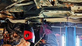 Welder sparks fly under raised car as mechanic repairs axle inside dim auto workshop - Powered by Shutterstock - Get 15% off with code: PIKWIZARD15