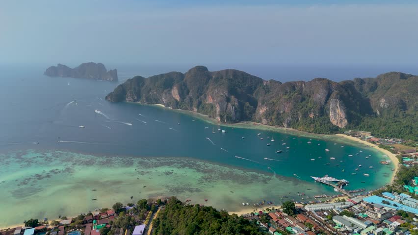 Discover the beautiful coastline in Thailand, featuring clear blue waters, lush greenery, and boats sailing in the distance. A perfect spot for relaxation and adventure during the day