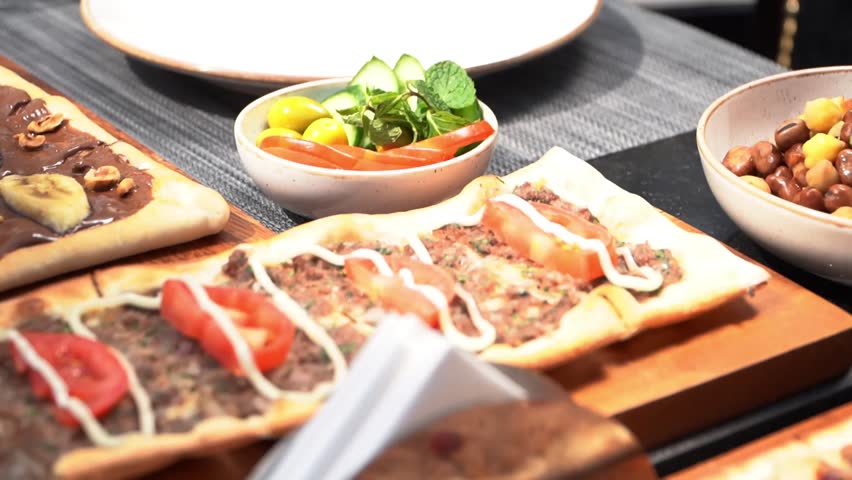 A selection of traditional Middle Eastern flatbreads topped with various ingredients, served in an elegant dining setting.