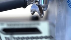 A close-up view of an espresso machine's portafilter, showcasing the pour of coffee into a shot glass. The image captures the metallic details and the brewing process. - Powered by Shutterstock - Get 15% off with code: PIKWIZARD15