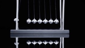 Newton's cradle pendulum with chrome steel balls demonstrating momentum transfer and physics principles on black background - Powered by Shutterstock - Get 15% off with code: PIKWIZARD15