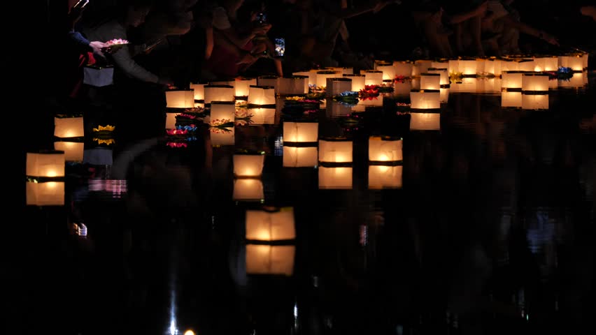 Floating paper lanterns illuminating river at night festival