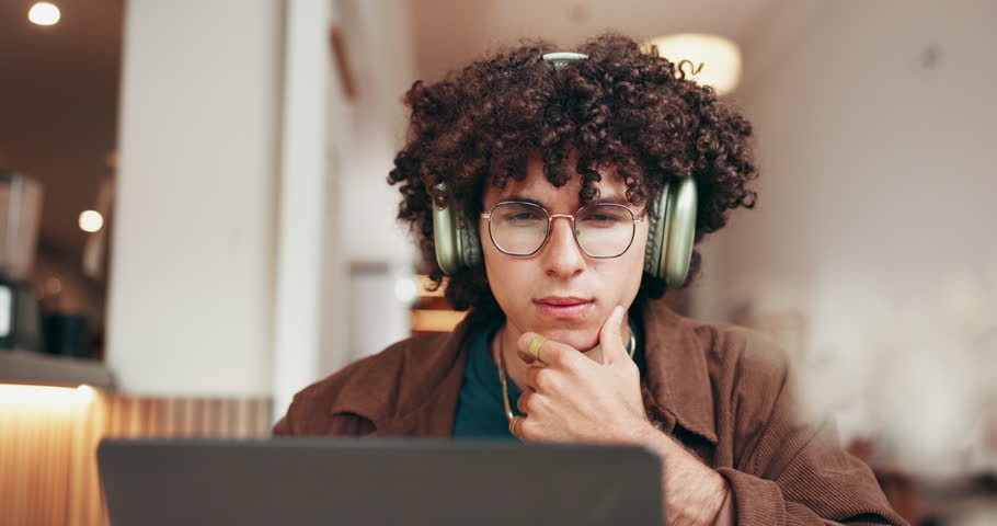 Headphone, education and man with laptop in coffee shop, streaming music and reading for scholarship. Audio tech, thinking and university student with pc for research, studying and learning in cafe.