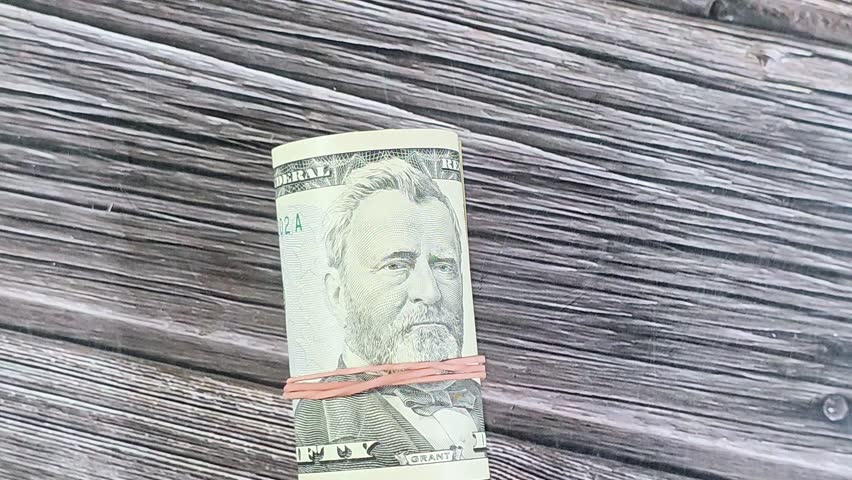 50 USD fifty American dollars banknotes cash money bills rolled up with a rubber band, features Ulysses S. Grant and the US capitol building, American money status concept, money exchange rate