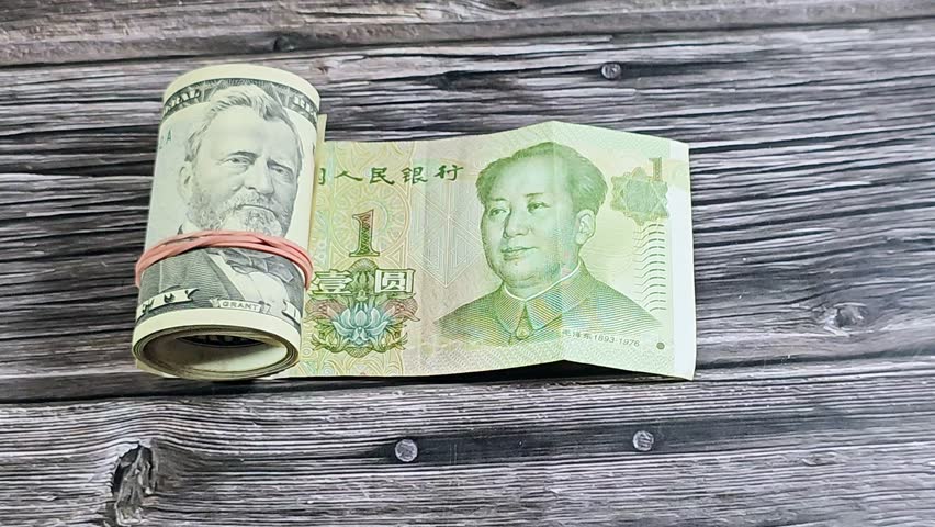 Chinese Yuan money bill and 50 USD fifty American dollars banknotes cash money rolled up with a rubber band, features Ulysses S. Grant, American and Chinese money, money exchange rate