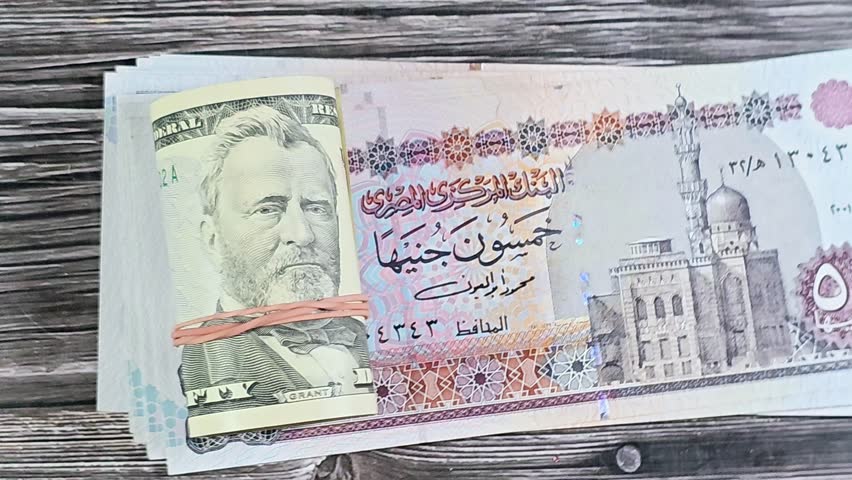 Egyptian money 50 EGP LE pounds bills and 50 USD fifty American dollars banknotes cash money rolled up with a rubber band, features Ulysses S. Grant, American and Egyptian money, money exchange rate