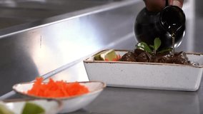 A close-up of a gourmet dish being garnished with olive oil in a restaurant setting. The dish includes fresh herbs and lime, with colorful garnishes on the side. - Powered by Shutterstock - Get 15% off with code: PIKWIZARD15