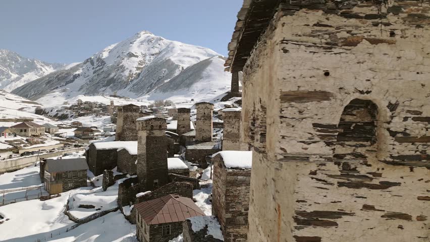 Aerial revealing view Ushguli village under bright sun snow covered mountains, UNESCO World Heritage Site in Svaneti Georgia. Chazhashi - most preserved village with svan towers
