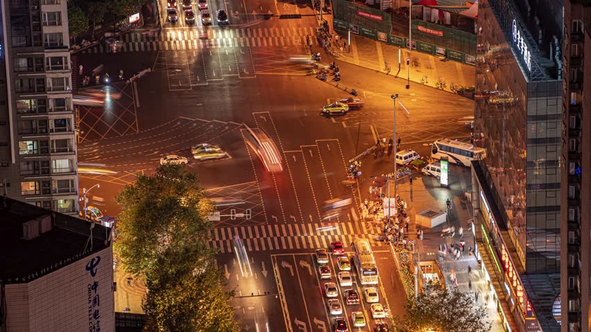 Aerial view of busy traffic intersection at night in Chunxi Road shopping district, Chengdu, China with illuminated streets and pedestrians
