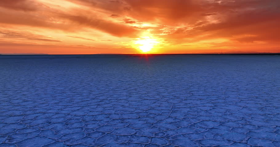 Beautiful setting sun over the horizon. Drone flight above the crusty blue salt pan in the Bonneville salt flats in Utah, USA.